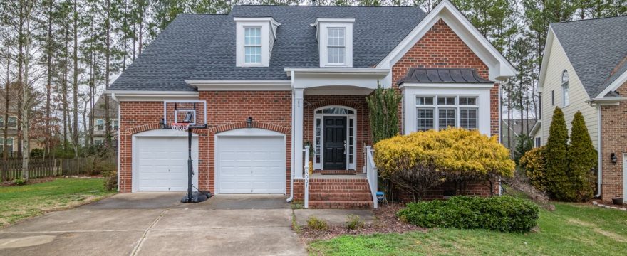 A brick house with an attached two-car garage with two white garage doors