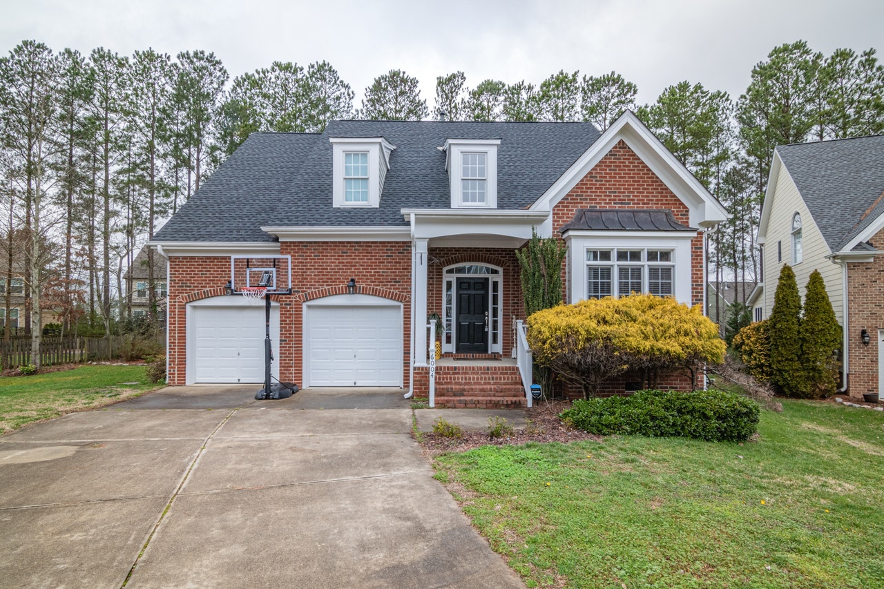 A brick house with an attached two-car garage with two white garage doors