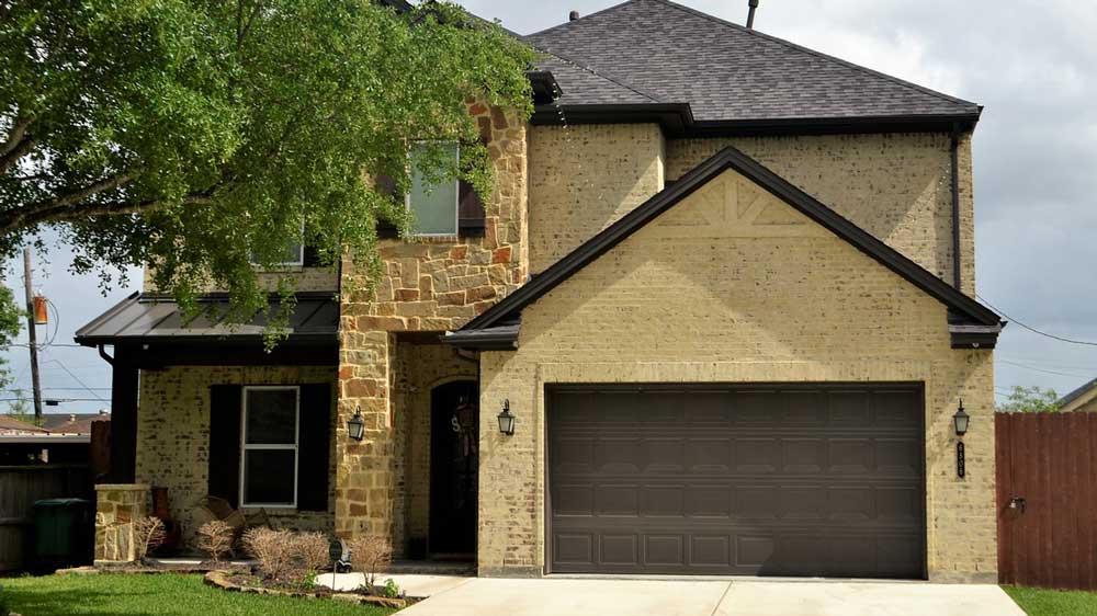 A yellow brick garage with a double-wide brown door.