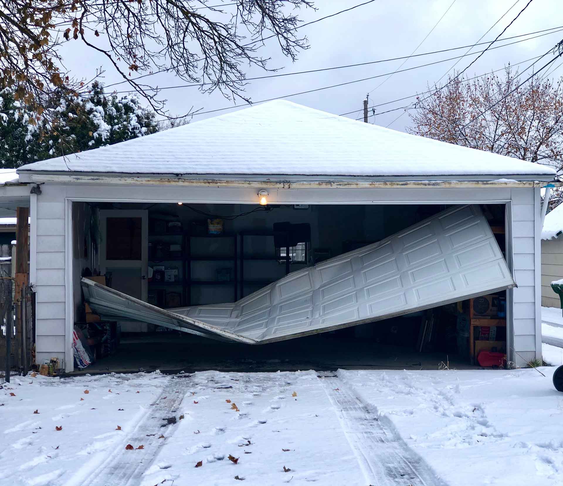 A crumpled garage door that has been completely blown off of it's hinges