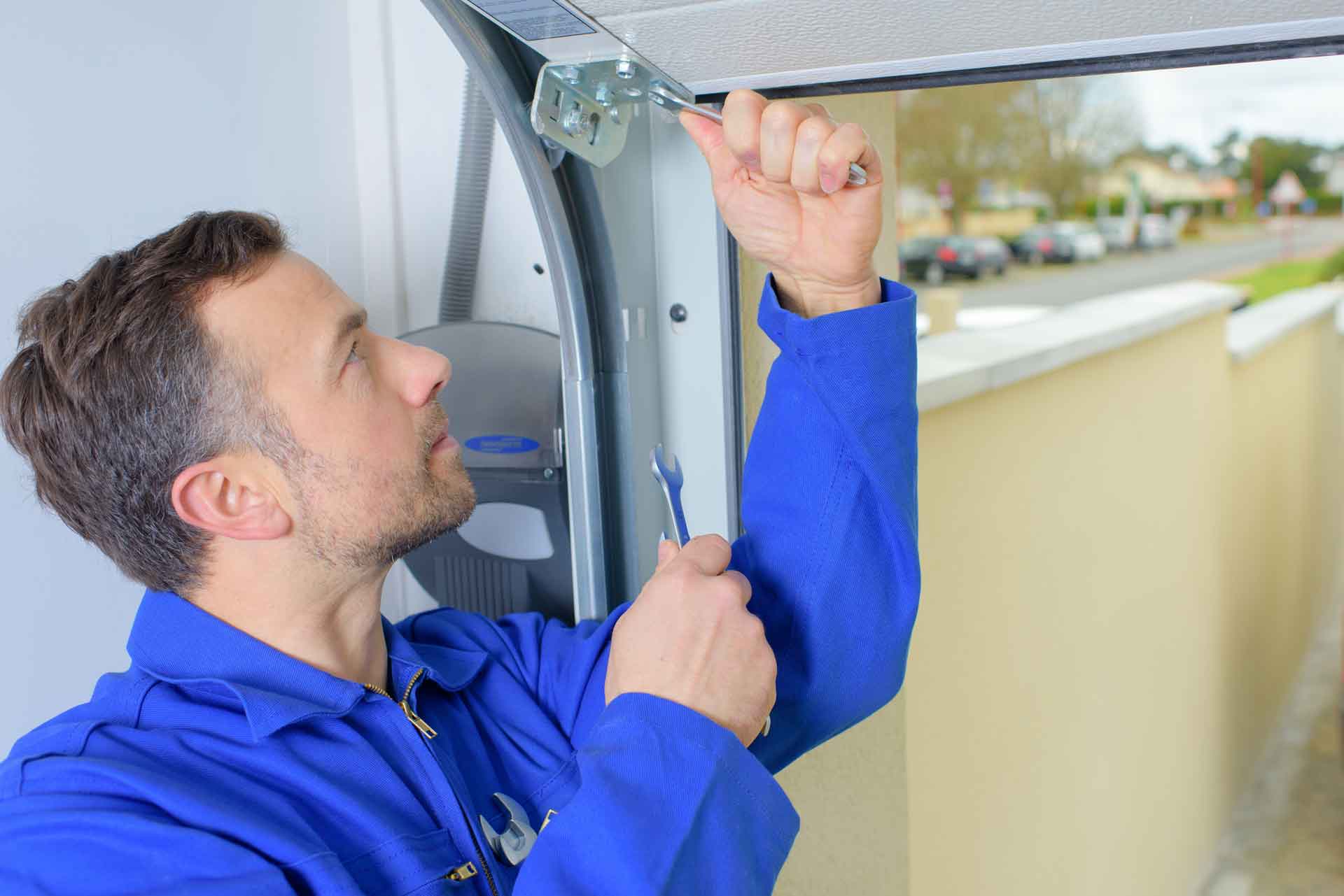 Garage door repair technician tightening a bolt on a garage door